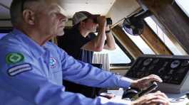 Aaron Smith peers through binoculars at ships installing the South Fork Wind project
